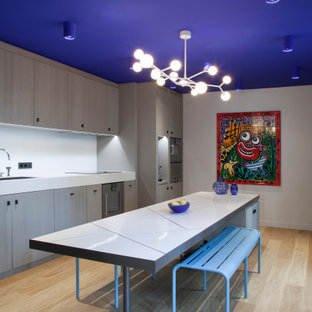 Photo of a contemporary kitchen in Paris with an undermount sink, flat-panel cabinets, grey cabinets, white splashback, light hardwood floors, with island, beige floor and white benchtop.