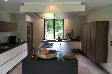 Cette image montre une cuisine encastrable design fermée avec un évier encastré, des portes de placard blanches, un sol en carrelage de céramique et îlot.
