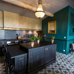 Aménagement d'une cuisine linéaire éclectique avec un placard avec porte à panneau surélevé, des portes de placard en bois vieilli, une crédence noire, un îlot central, un sol multicolore et un plan de travail noir.