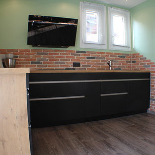 Mid-sized modern open concept kitchen inspiration - Mid-sized minimalist l-shaped linoleum floor and gray floor open concept kitchen photo in Lyon with a single-bowl sink, wood countertops, multicolored backsplash, brick backsplash, black appliances and brown countertops