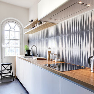 Exemple d'une cuisine linéaire tendance fermée et de taille moyenne avec un placard à porte plane, des portes de placard blanches, un plan de travail en bois, une crédence multicolore et aucun îlot.