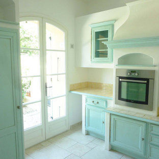 Ispirazione per una cucina ad U country chiusa e di medie dimensioni con lavello sottopiano, ante con riquadro incassato, ante turchesi, top piastrellato, paraspruzzi beige, paraspruzzi con piastrelle in terracotta, elettrodomestici da incasso, pavimento con piastrelle in ceramica, pavimento beige e top beige
