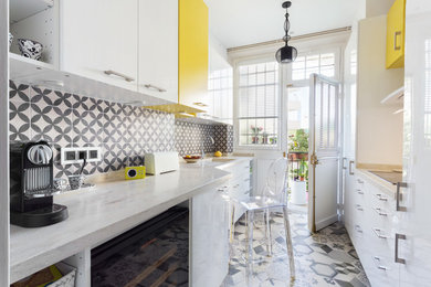 パリにある高級な中くらいなコンテンポラリースタイルのおしゃれなキッチン (一体型シンク、フラットパネル扉のキャビネット、白いキャビネット、クオーツストーンカウンター、マルチカラーのキッチンパネル、セメントタイルのキッチンパネル、パネルと同色の調理設備、セメントタイルの床、アイランドなし、白い床) の写真