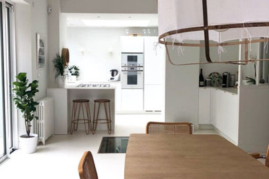 Design ideas for a small modern u-shaped open plan kitchen in Nantes with a single-bowl sink, white cabinets, composite countertops, white appliances, concrete flooring, an island, white floors and white worktops.