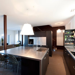 Réalisation d'une grand cuisine ouverte design en U avec un évier intégré, un placard à porte plane, des portes de placard noires, moquette et un îlot central.