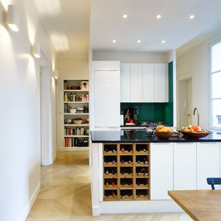 Réalisation d'une grand cuisine ouverte parallèle design avec des portes de placard blanches et un îlot central.