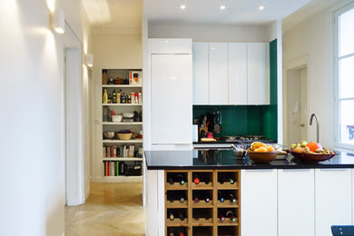 Réalisation d'une grande cuisine ouverte parallèle design avec des portes de placard blanches et îlot.