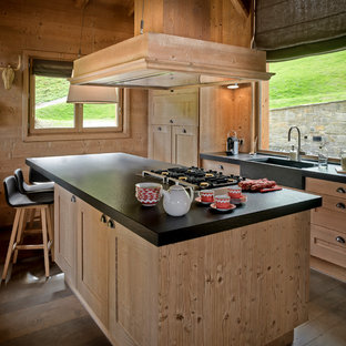Aménagement d'une cuisine américaine linéaire montagne de taille moyenne avec un évier intégré, un placard à porte shaker, des portes de placard en bois clair, un électroménager encastrable, un sol en bois brun et un îlot central.