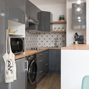 Exemple d'une petit cuisine américaine scandinave en L avec un évier posé, un placard à porte affleurante, des portes de placard grises, un plan de travail en stratifié, une crédence grise, une crédence en carreau de ciment, un électroménager encastrable, un sol en contreplaqué, un sol beige et un plan de travail beige.