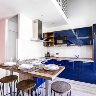 Idées déco pour une cuisine américaine contemporaine en U de taille moyenne avec un évier 1 bac, des portes de placard bleues, un plan de travail en stratifié, une crédence beige, un électroménager encastrable, un sol en vinyl, un placard à porte plane et aucun îlot.