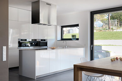 Inspiration för moderna linjära kök med öppen planlösning, med en undermonterad diskho, luckor med profilerade fronter, vita skåp, bänkskiva i kvartsit, rostfria vitvaror och en köksö