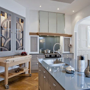 Idée de décoration pour une grand cuisine américaine tradition en L avec un évier 2 bacs, des portes de placard grises, un électroménager en acier inoxydable, un sol en bois brun et un îlot central.