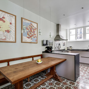 Cette image montre une grand cuisine américaine bohème en U avec un évier encastré, un plan de travail en granite, un électroménager en acier inoxydable, un sol en carrelage de céramique, un placard à porte plane, des portes de placard grises, une péninsule, une crédence métallisée et une crédence en dalle métallique.