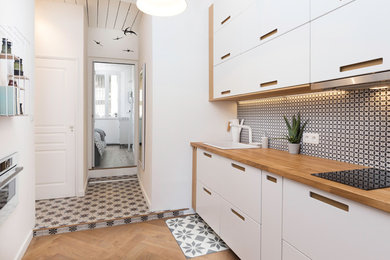 Foto på ett litet maritimt kök, med en integrerad diskho, vita skåp, träbänkskiva, flerfärgad stänkskydd, stänkskydd i cementkakel, vita vitvaror och ljust trägolv