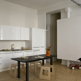 Réalisation d'une grand cuisine américaine linéaire design avec un évier intégré, un placard à porte plane, des portes de placard blanches, un plan de travail en inox et aucun îlot.