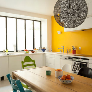 Exemple d'une grand cuisine américaine tendance en L avec un placard à porte plane, des portes de placard blanches, un électroménager en acier inoxydable et aucun îlot.