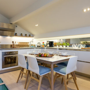 Idées déco pour une cuisine américaine contemporaine en U de taille moyenne avec des portes de placard blanches, un électroménager encastrable et un sol en bois clair.