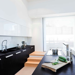 Inspiration pour une grand cuisine ouverte parallèle design avec des portes de placard noires et un îlot central.
