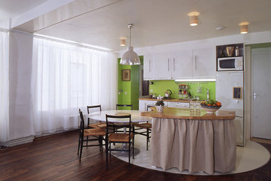 Идея дизайна: прямая кухня среднего размера в стиле модернизм с обеденным столом, врезной мойкой, фасадами с декоративным кантом, белыми фасадами, деревянной столешницей, зеленым фартуком, фартуком из дерева, белой техникой, бетонным полом и островом