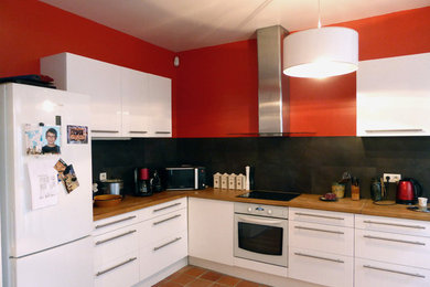 パリにあるお手頃価格の広いコンテンポラリースタイルのおしゃれなキッチン (ダブルシンク、インセット扉のキャビネット、白いキャビネット、木材カウンター、黒いキッチンパネル、セラミックタイルのキッチンパネル、白い調理設備、テラコッタタイルの床、オレンジの床) の写真