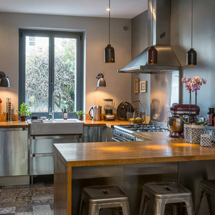 Aménagement d'une cuisine américaine éclectique en U de taille moyenne avec une façade en inox, une péninsule, un évier intégré, un sol en carreaux de ciment et un sol gris.
