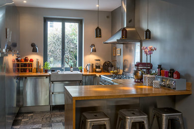 Exempel på ett mellanstort eklektiskt kök, med skåp i rostfritt stål, en halv köksö, en integrerad diskho, cementgolv och grått golv