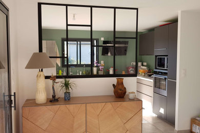 Cette image montre une cuisine ouverte minimaliste en U de taille moyenne avec un placard à porte affleurante, des portes de placard grises, un électroménager noir, aucun îlot et un plan de travail blanc.