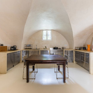 Réalisation d'une cuisine américaine sud-ouest américain en U avec un évier posé, un placard à porte plane, une façade en inox, un électroménager en acier inoxydable, aucun îlot, un sol beige et un plan de travail beige.