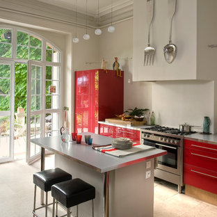Inspiration pour une cuisine américaine parallèle design de taille moyenne avec un placard à porte plane, des portes de placard rouges, un électroménager en acier inoxydable et un îlot central.