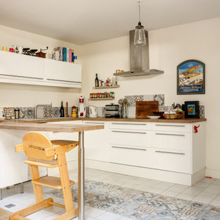Aménagement d'une cuisine éclectique en U avec un placard à porte plane, des portes de placard blanches, une péninsule, un sol multicolore et un plan de travail blanc.