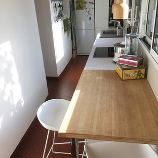 ナントの小さいモダンスタイルのおしゃれなキッチン (シングルシンク、白いキャビネット、ラミネートカウンター、白いキッチンパネル、ガラス板のキッチンパネル、黒い調理設備、テラコッタタイルの床、アイランドなし、赤い床) の写真