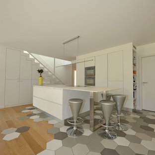 Inspiration pour une cuisine américaine parallèle design de taille moyenne avec un placard à porte affleurante, des portes de placard blanches et une péninsule.