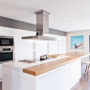 Réalisation d'une grand cuisine américaine linéaire design avec un placard à porte plane, des portes de placard blanches et un îlot central.
