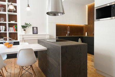 Ispirazione per una grande cucina contemporanea con lavello sottopiano, ante nere, top in marmo, paraspruzzi a effetto metallico, elettrodomestici neri, parquet chiaro e top nero