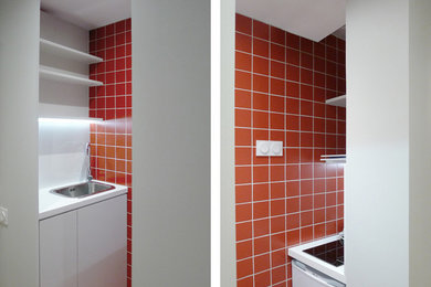 Idée de décoration pour une petite cuisine parallèle minimaliste fermée avec un évier encastré, un plan de travail en stratifié, une crédence rouge, une crédence en céramique, un électroménager blanc et un sol en carrelage de céramique.