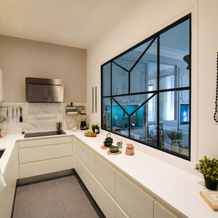 Inspiration pour une cuisine design en U de taille moyenne et fermée avec un évier encastré, des portes de placard blanches, un plan de travail en quartz modifié, une crédence en dalle de pierre, un sol en carrelage de céramique, un placard à porte plane, un électroménager en acier inoxydable, aucun îlot, une crédence blanche et un sol marron.