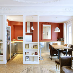 Inspiration pour une cuisine américaine design en L de taille moyenne avec un sol en bois clair, un évier posé, un placard à porte plane, une façade en inox, un plan de travail en bois, une crédence rouge, un électroménager en acier inoxydable et un îlot central.