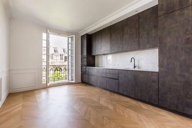Large trendy single-wall light wood floor enclosed kitchen photo in Paris with an integrated sink, beaded inset cabinets, distressed cabinets, solid surface countertops, white backsplash, marble backsplash, black appliances and no island