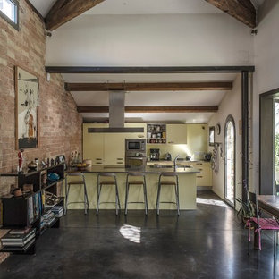 Réalisation d'une grand cuisine ouverte parallèle champêtre avec des portes de placard jaunes et une péninsule.