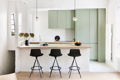 Cette image montre une cuisine parallèle design avec un évier posé, un placard à porte plane, des portes de placards vertess, un plan de travail en bois, une péninsule, un sol blanc, un plan de travail beige et papier peint.