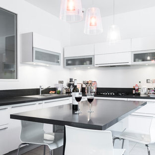 Idées déco pour une cuisine contemporaine en L avec un évier posé, un placard à porte plane, des portes de placard blanches, un électroménager en acier inoxydable, un îlot central, un sol gris et un plan de travail noir.