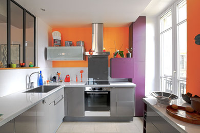 Cette image montre une cuisine ouverte encastrable design en U de taille moyenne avec un placard à porte affleurante, des portes de placard violettes, une crédence en carreau de verre et une péninsule.