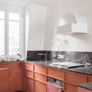 Cette image montre une cuisine design en U avec un évier encastré, des portes de placard oranges, une crédence multicolore, une crédence en dalle de pierre, un électroménager en acier inoxydable, un sol orange et un plan de travail multicolore.