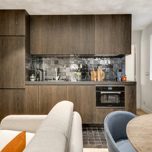 Photo of a mid-sized contemporary single-wall open plan kitchen in Paris with a single-bowl sink, dark wood cabinets, black splashback, terra-cotta splashback, panelled appliances, no island, beaded inset cabinets and terra-cotta floors.
