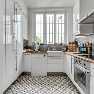 Idée de décoration pour une cuisine grise et blanche nordique en U fermée et de taille moyenne avec des portes de placard blanches, un plan de travail en bois, une crédence grise, un électroménager en acier inoxydable, aucun îlot, un évier de ferme, un placard à porte affleurante, une crédence en mosaïque et un sol en carreaux de ciment.