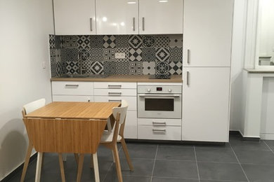 Aménagement d'une petite cuisine ouverte linéaire moderne avec des portes de placard blanches, un plan de travail en bois, carreaux de ciment au sol et un sol gris.