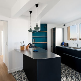 Aménagement d'une cuisine parallèle contemporaine avec un évier intégré, un placard à porte plane, des portes de placard noires, un plan de travail en inox, un électroménager en acier inoxydable, une péninsule et un sol multicolore.