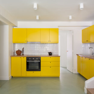 Inspiration pour une cuisine design en U de taille moyenne avec un évier posé, un placard à porte plane, des portes de placard jaunes, un plan de travail en bois, une crédence blanche, une crédence en carreau de céramique, aucun îlot, un sol vert et un plan de travail beige.