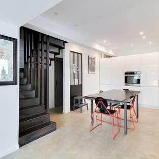Réalisation d'une cuisine américaine design en L avec un placard à porte plane, des portes de placard blanches, un plan de travail en bois, un électroménager en acier inoxydable, béton au sol, aucun îlot, un sol beige et un plan de travail beige.
