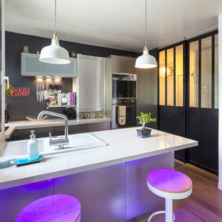 Inspiration pour une cuisine américaine design en U de taille moyenne avec une façade en inox, une crédence grise et une péninsule.